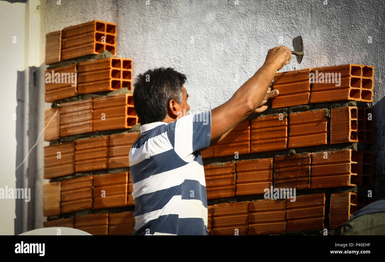 Em construção Pedreiros levantando parede de tijolos. Foto de stock
