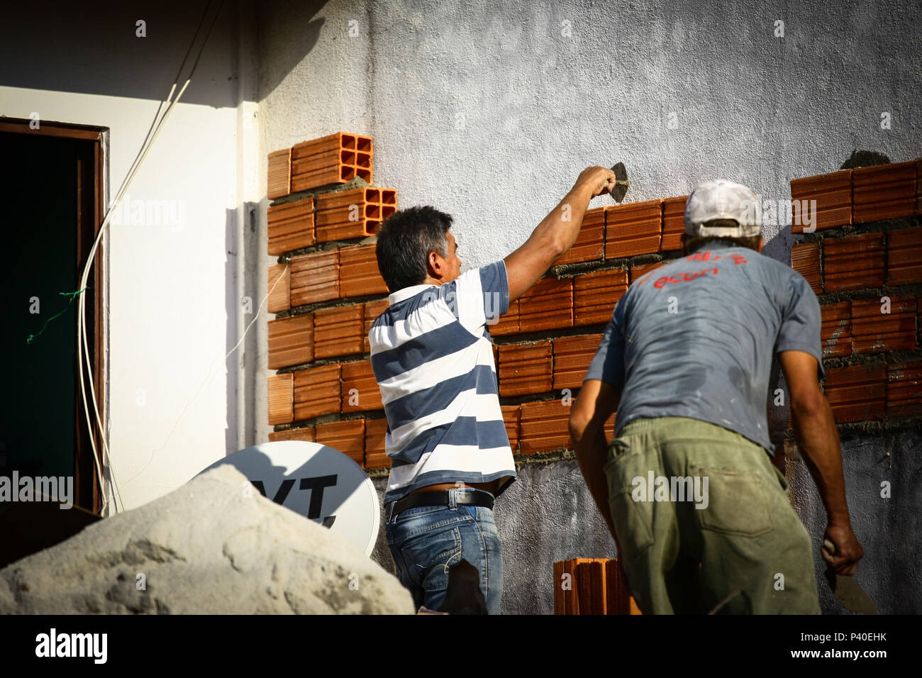 Em construção Pedreiros levantando parede de tijolos. Foto de stock