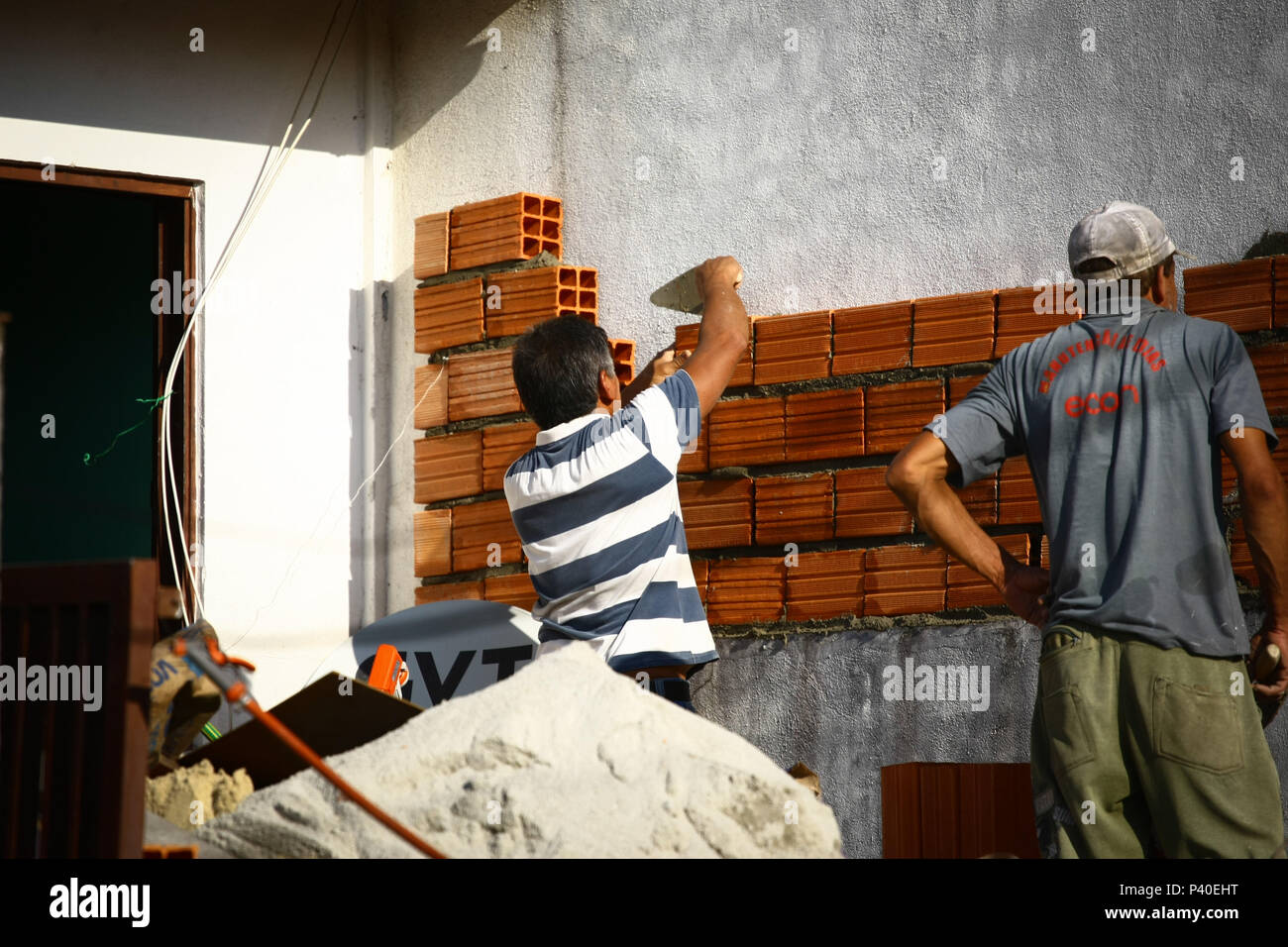 Em construção Pedreiros levantando parede de tijolos. Foto de stock