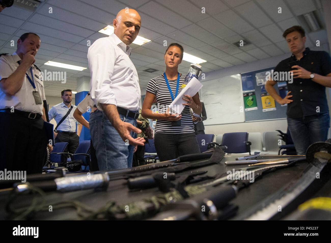 Home Secretario Sajid Javid (segunda a la izquierda) mira a las armas confiscadas, durante una visita a la Comisaría de Islington en Londres, por delante de la Ley de armas ofensivas se introdujo en el Parlamento el miércoles. Foto de stock