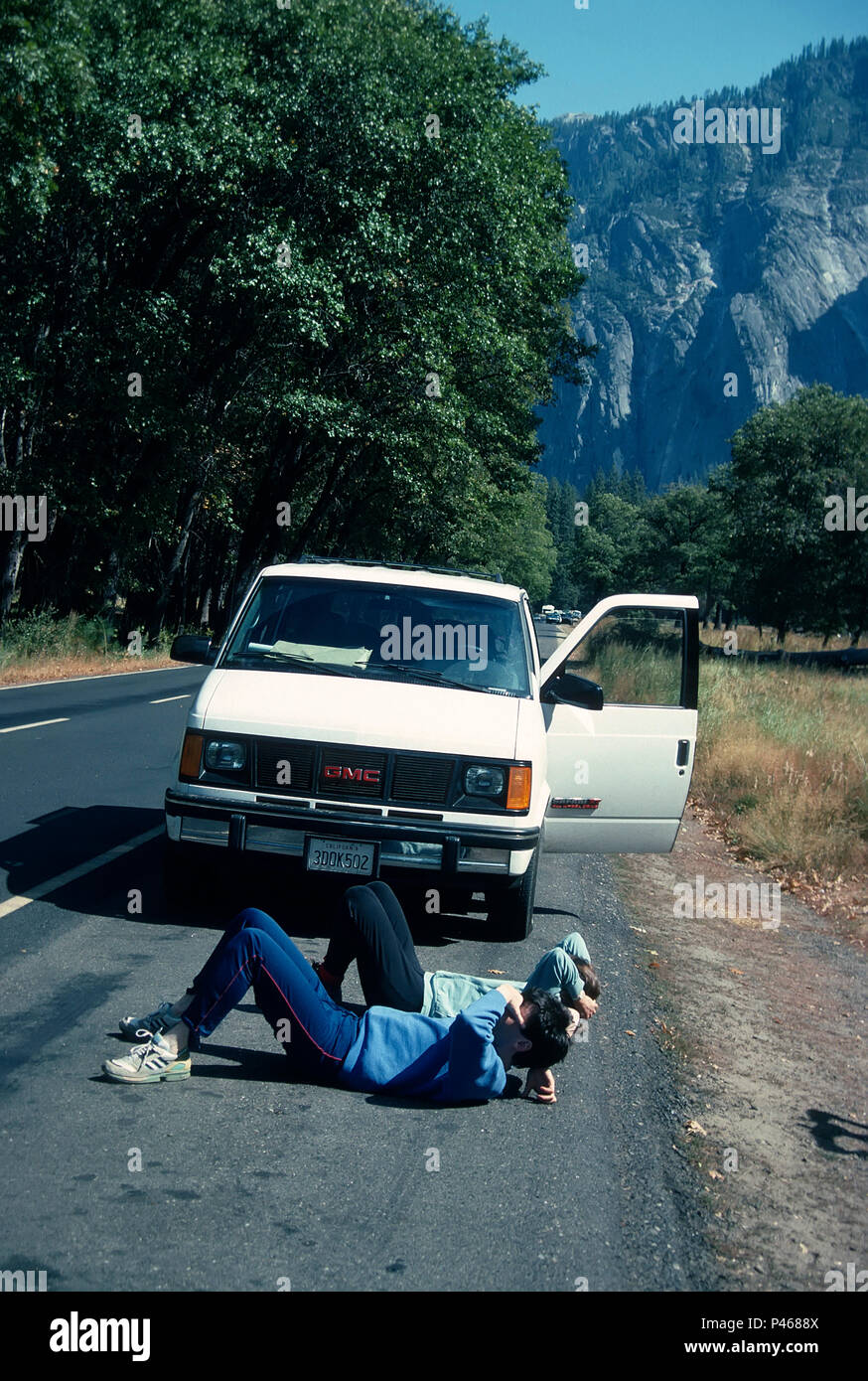 Dos turistas Acuéstese sobre su espalda, hijo de la carretera para mirar El Capitan, Yosemite, California Foto de stock