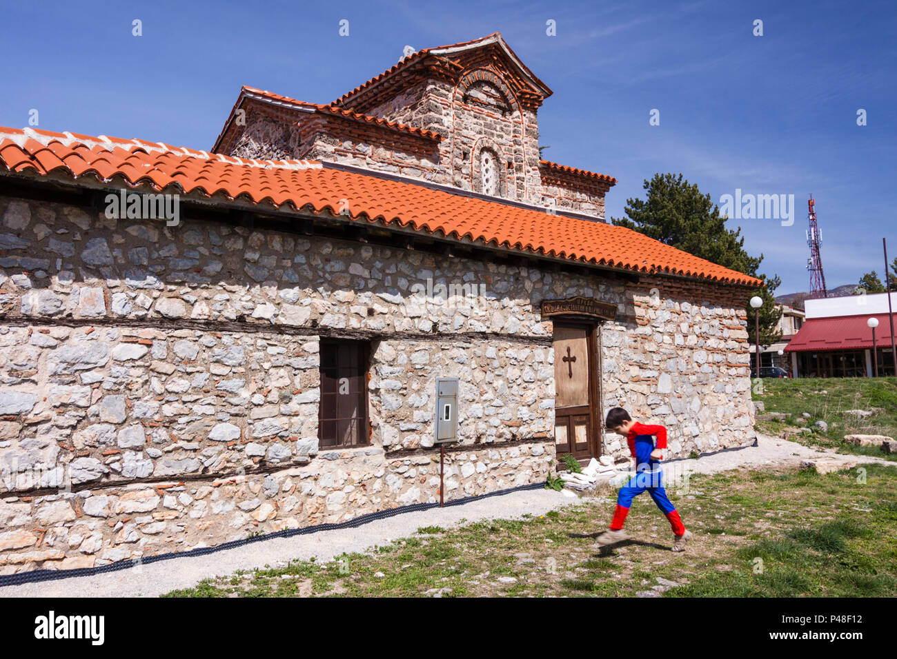 Ohrid, República de Macedonia: un niño en un traje de Spiderman camina más allá de la santísima Madre de Dios Peribleptos iglesia (1295) una de las iglesias más antiguas Foto de stock