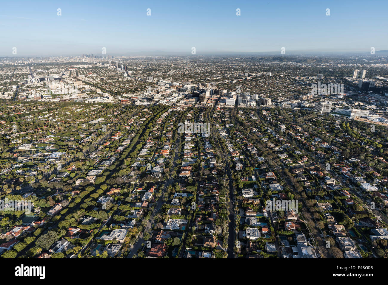 Por la tarde vista aérea de las calles de Beverly Hills con Mid Wilshire y el centro de Los Angeles, California en el fondo. Foto de stock