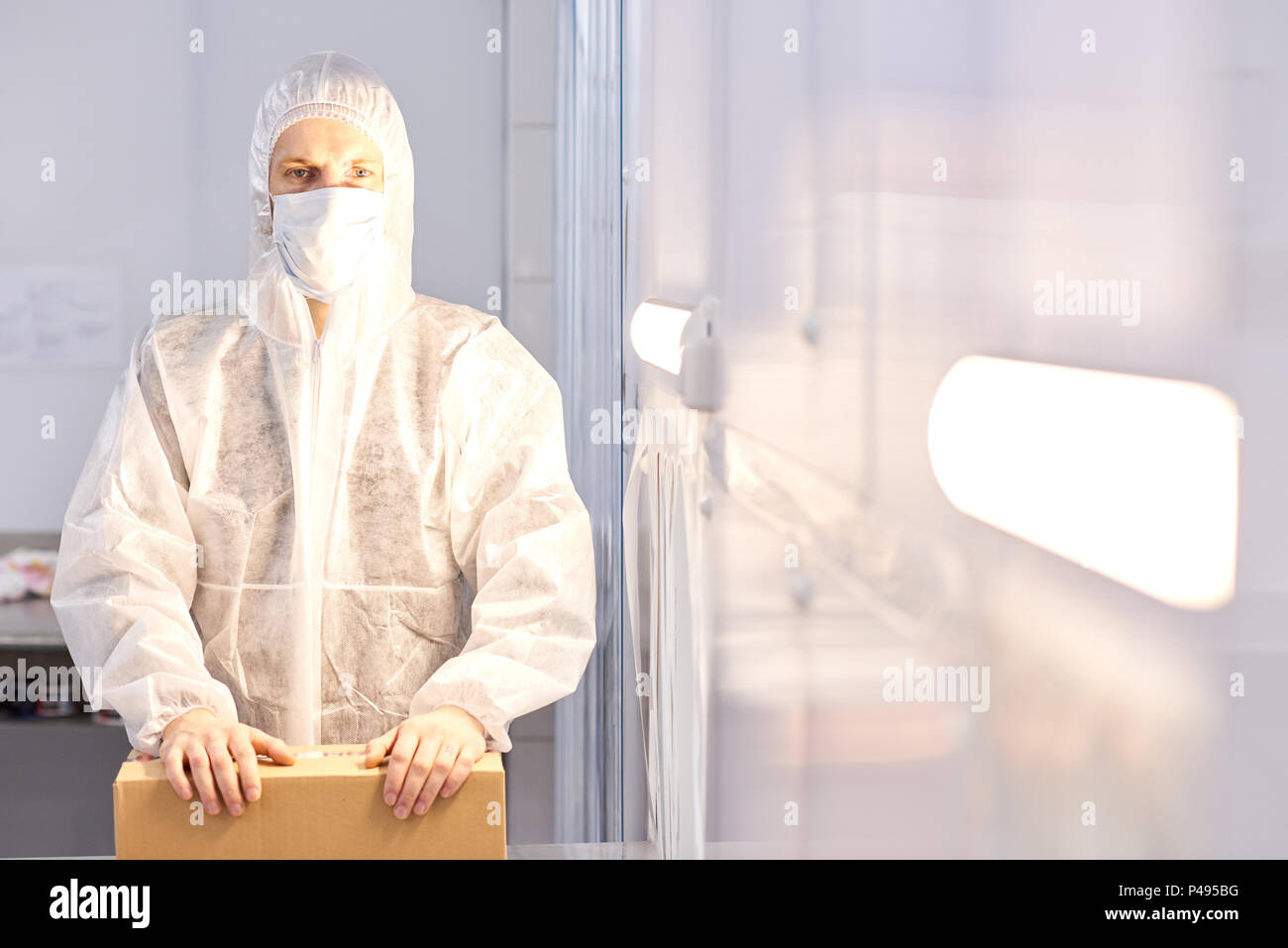 Trabajador de la fábrica con una caja con ropa protectora permanente Foto de stock