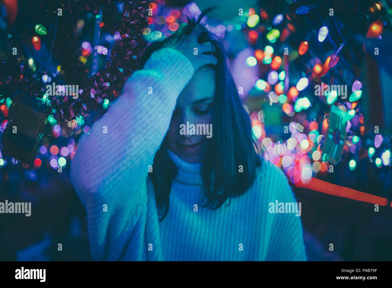 Mujer morena moviendo su cabello entre luces de Navidad Foto de stock
