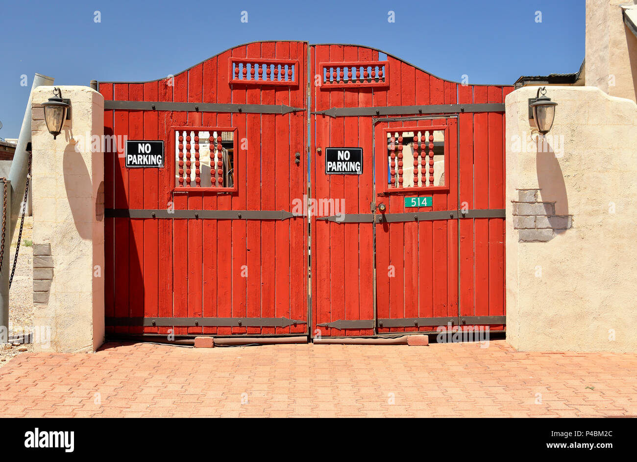 Puerta de madera roja en una pared de adobe en la brillante luz del sol Foto de stock