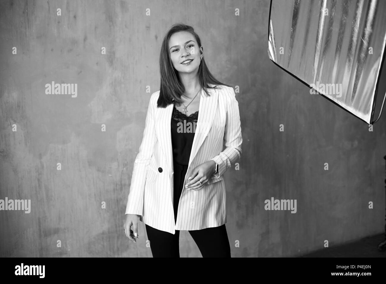 Hermosa joven mujer bonita con pelo recto largo vistiendo negro blusa y  pantalones y chaqueta de rayas blancas riendo, sonriendo y posando y  soporte Fotografía de stock - Alamy