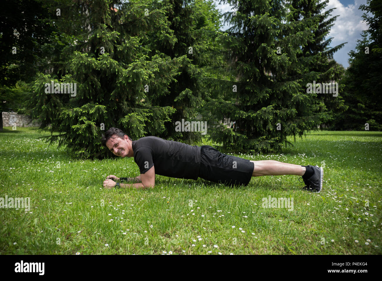 Hombre haciendo flexiones en un parque público Foto de stock