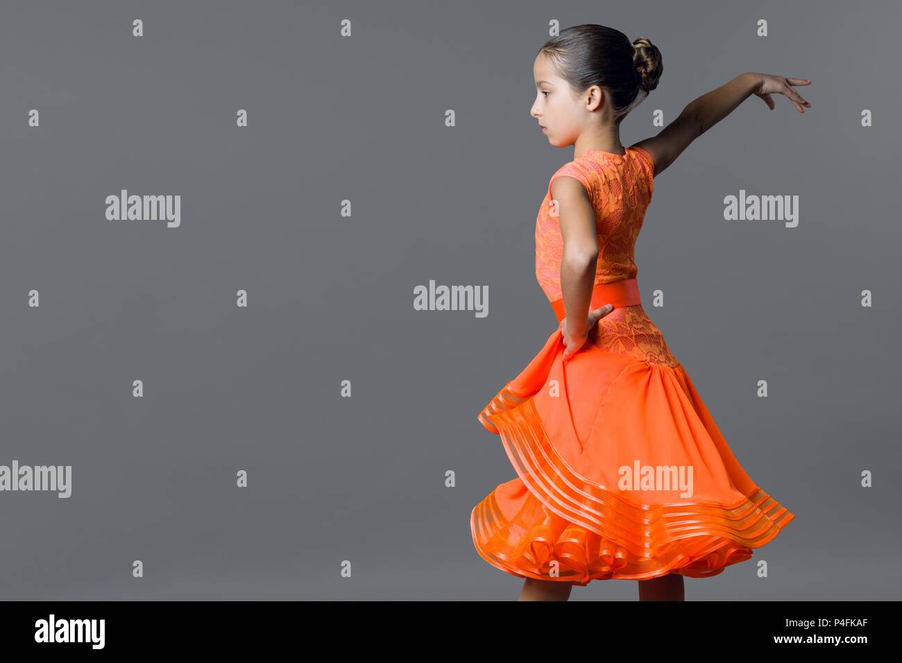 Retrato de una niña 9-10 años bailarina. Deportes, baile latino. Chica en un vestido de color naranja sobre fondo gris de studio, espacio de copia Fotografía de stock - Alamy