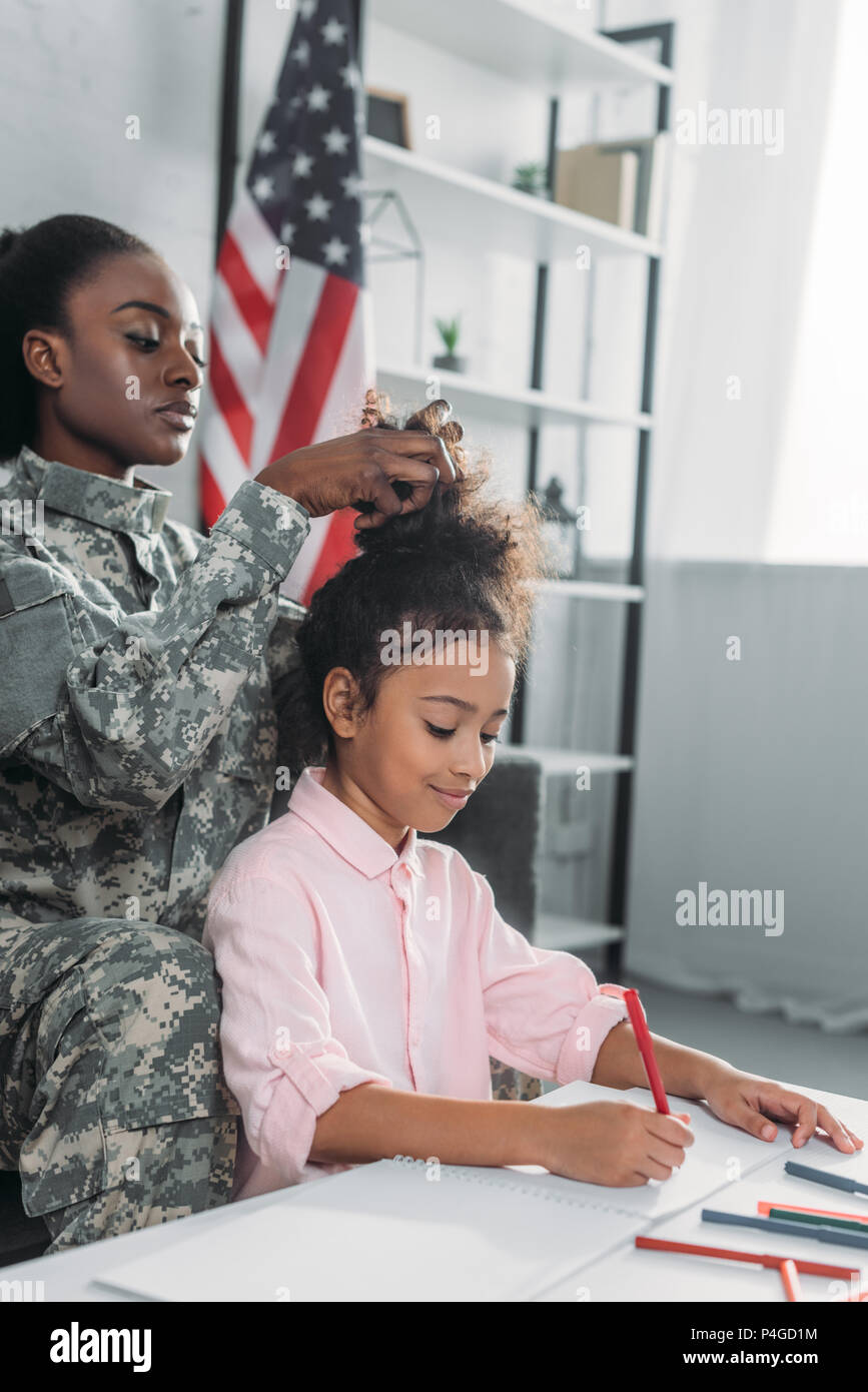 Mujer soldado americano africano peinado de fijación hija ocupado con el  dibujo de la tabla Fotografía de stock - Alamy