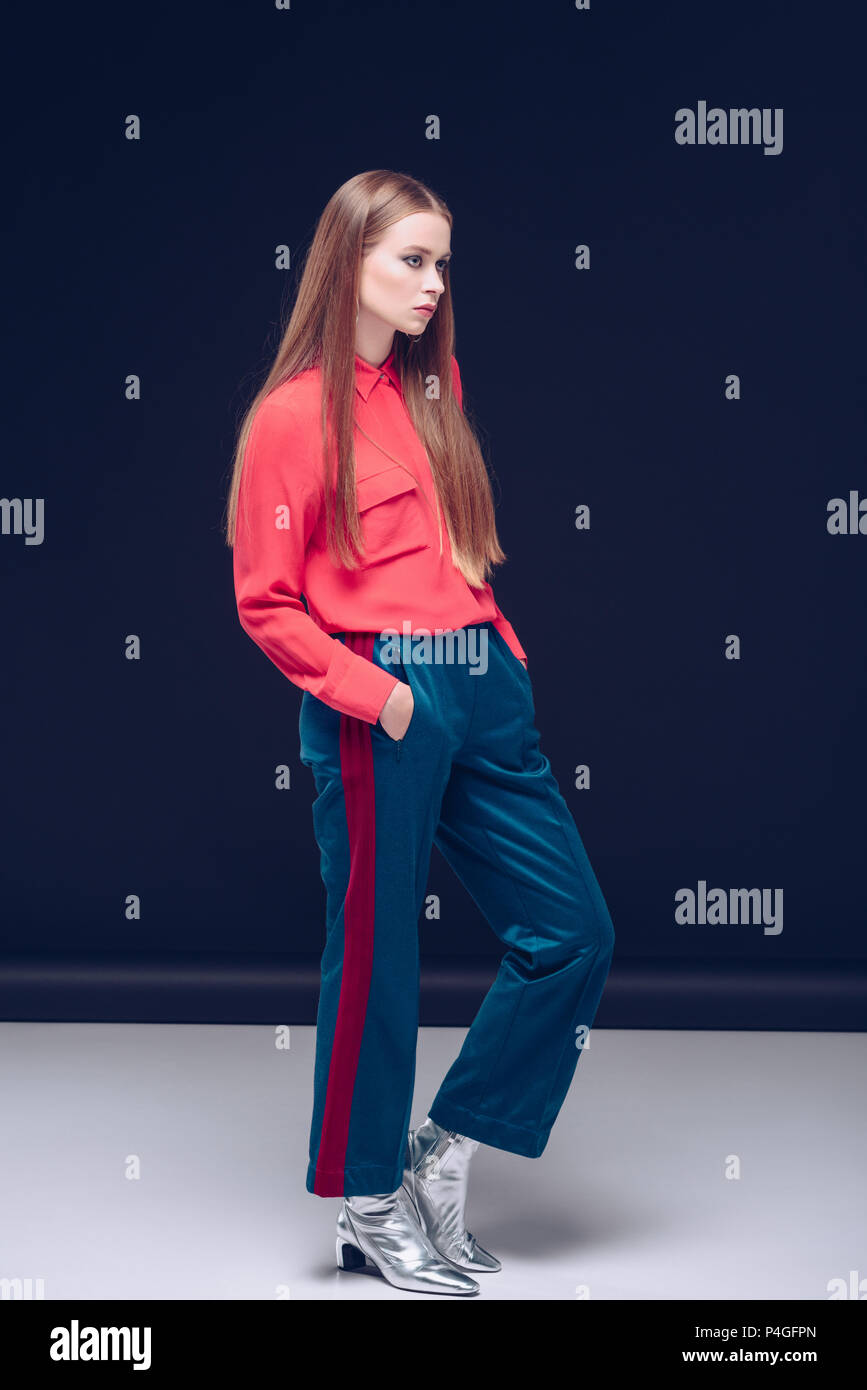 Mujer atractiva en camisa roja, pantalones y zapatos de plata posando sobre  negro Fotografía de stock - Alamy