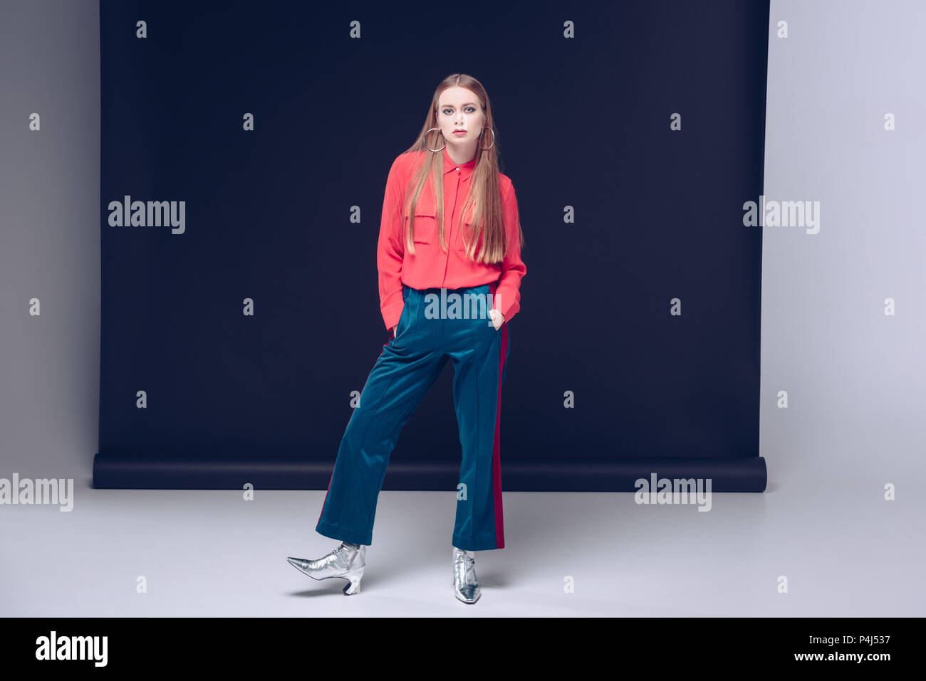 Bella mujer en camisa roja, pantalones y zapatos de plata posando sobre  negro Fotografía de stock - Alamy