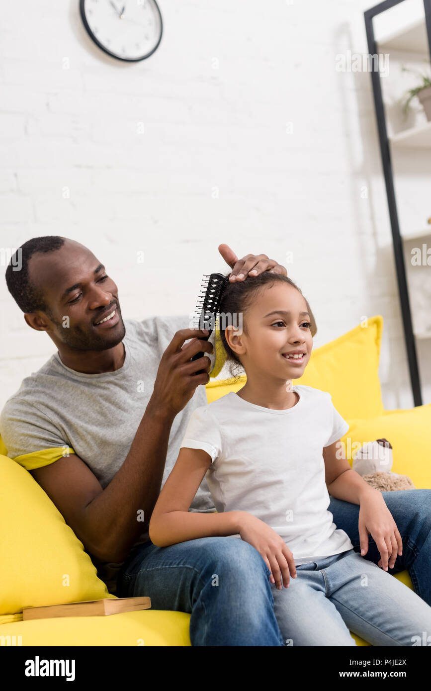 Padre peinando el cabello de su hija mientras estaba sentado detrás de ella  en la cama Fotografía de stock  Alamy