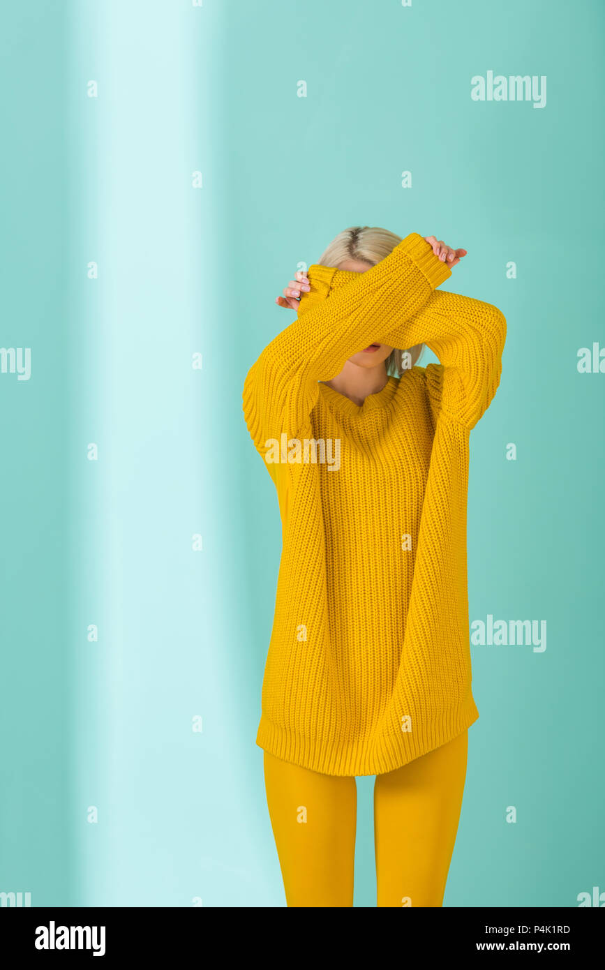obra maestra Granjero Grafico Oculta la vista de mujer en jersey amarillo y leotardos posando sobre fondo  azul Fotografía de stock - Alamy