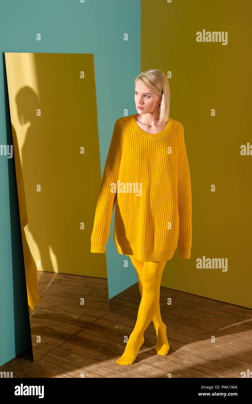 Presta atención a Sueño áspero colonia Pensativo hermosa mujer rubia en jersey amarillo y leotardos de pie en el  espejo Fotografía de stock - Alamy