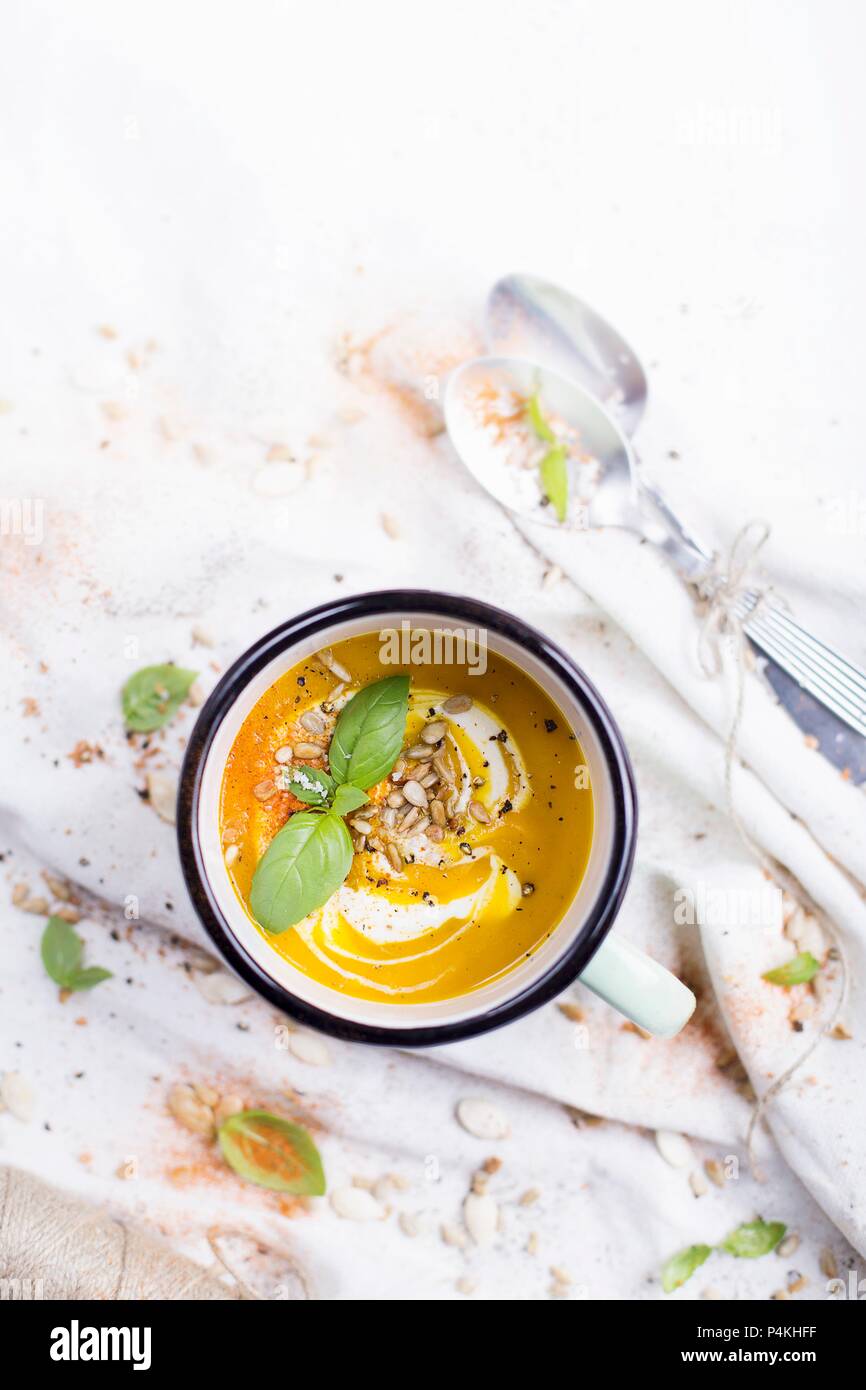 Sopa de calabaza en una taza de esmalte; decoradas con albahaca fresca y  semillas de girasol Fotografía de stock - Alamy