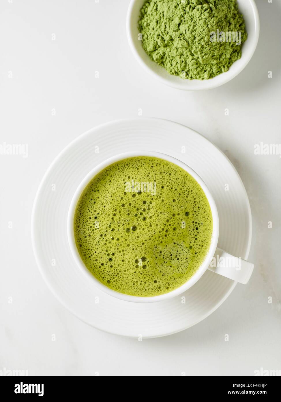 Una taza de té matcha y un tazón de polvo de té (ver arriba) Foto de stock