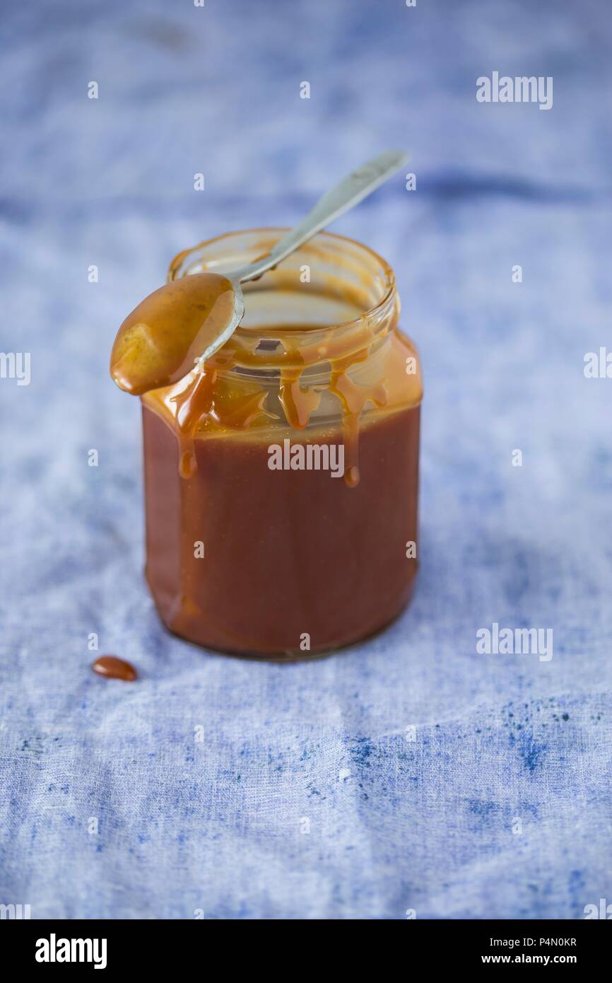 Salsa de Caramelo casero en una jarra con una cuchara Foto de stock