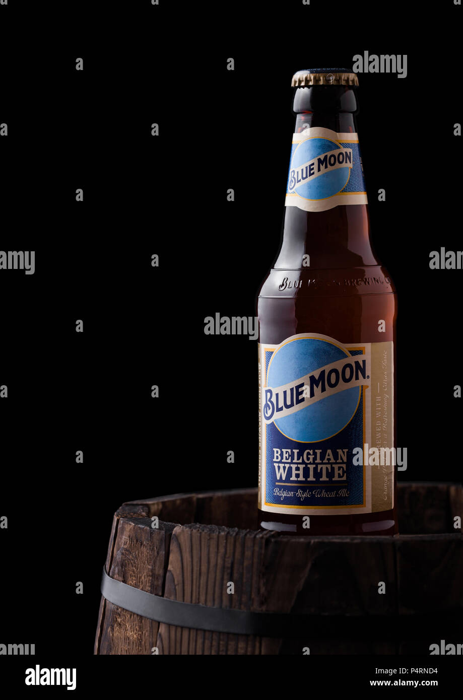 Londres, Reino Unido - 06 de junio de 2018: una botella de cerveza blanca belga Blue Moon, fabricada por MillerCoors viejo barril de madera sobre fondo negro. Foto de stock