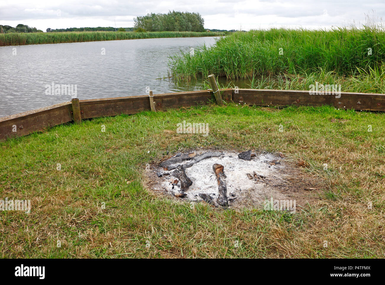 Los restos de un pequeño fuego en las orillas del río Bure en el Norfolk Broads en Upton, Norfolk, Inglaterra, Reino Unido, Europa. Foto de stock