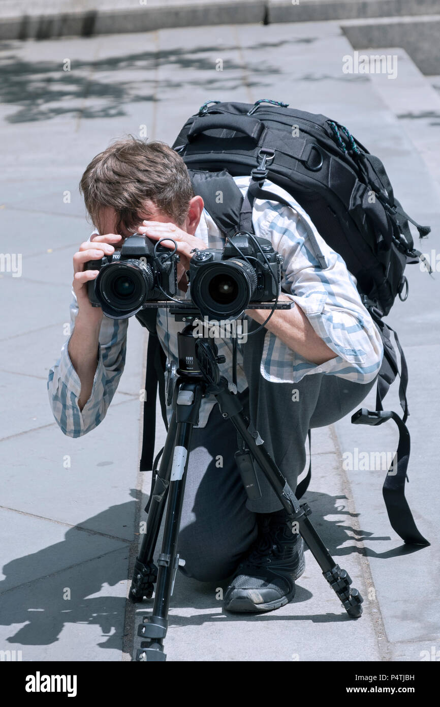 Un hombre filmar o fotografiar con dos cámaras a la vez fuera de la rama principal de la biblioteca pública en el centro de Manhattan, Ciudad de Nueva York Foto de stock