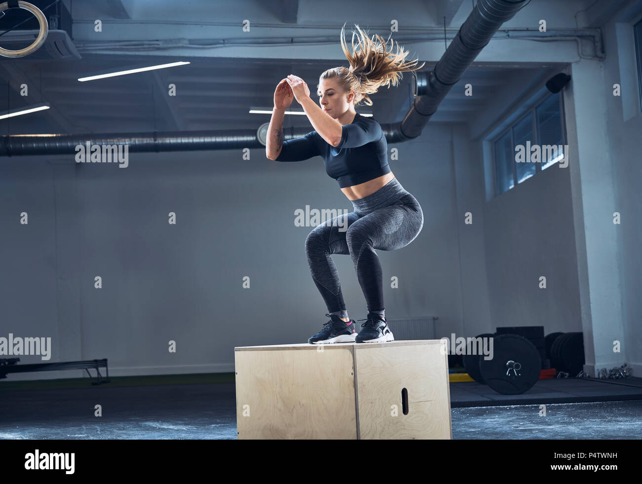 Mujer atlética haciendo ejercicio en el gimnasio de salto cuadro Foto de stock