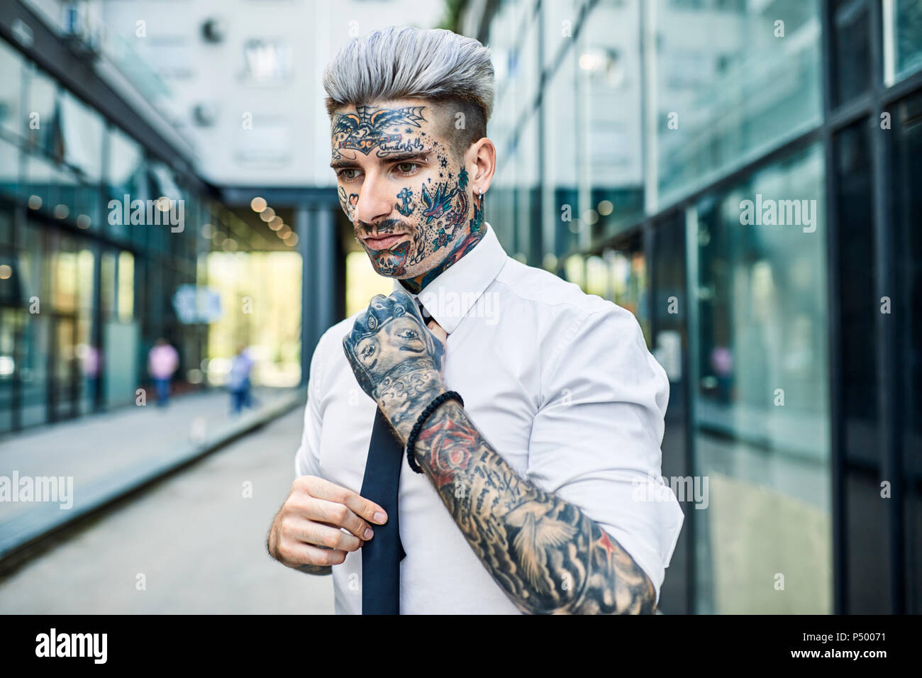 Empresario joven con cara tatuada, sujeción tie Foto de stock
