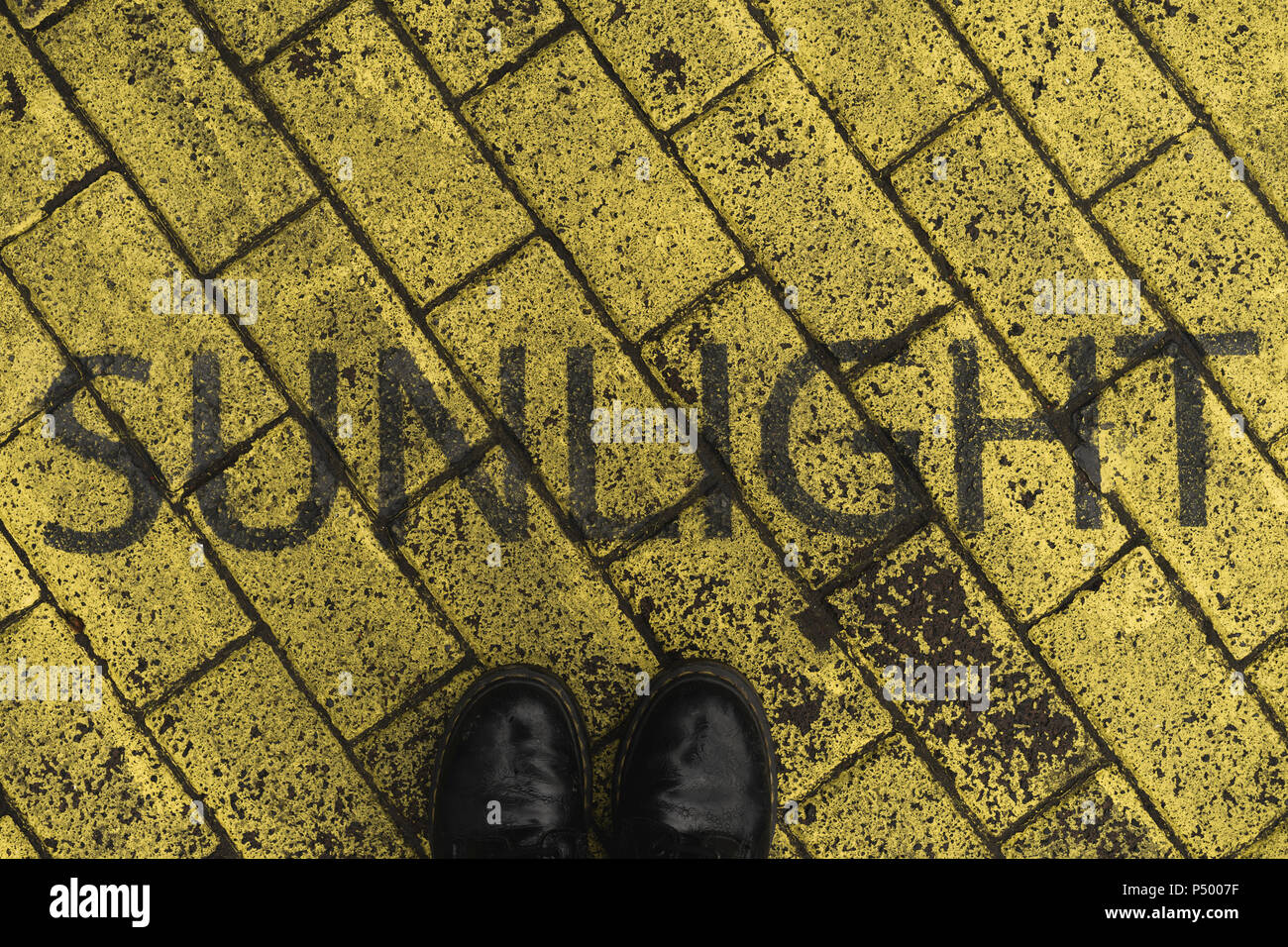 Zapatos Negros sobre amarillo con pavimento estarcida palabra 'Sunlight'  Fotografía de stock - Alamy