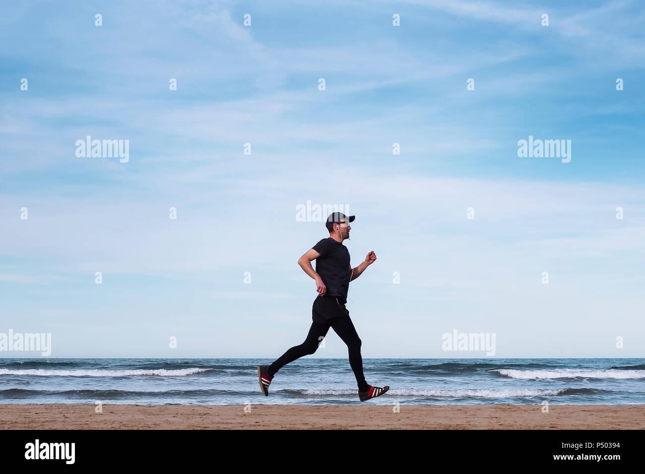 España, el hombre vestido de negro, trotar en la playa Foto de stock