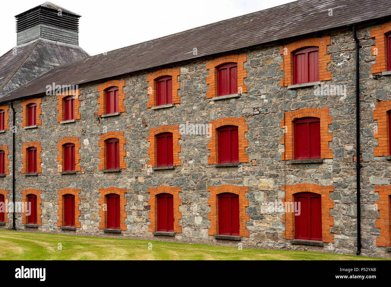 Midleton Distillery antiguo edificio industrial con ventanas rojas y piedra Paredes fachada detalles de la destilería Old Jameson Whiskey in Midleton Irlanda Foto de stock