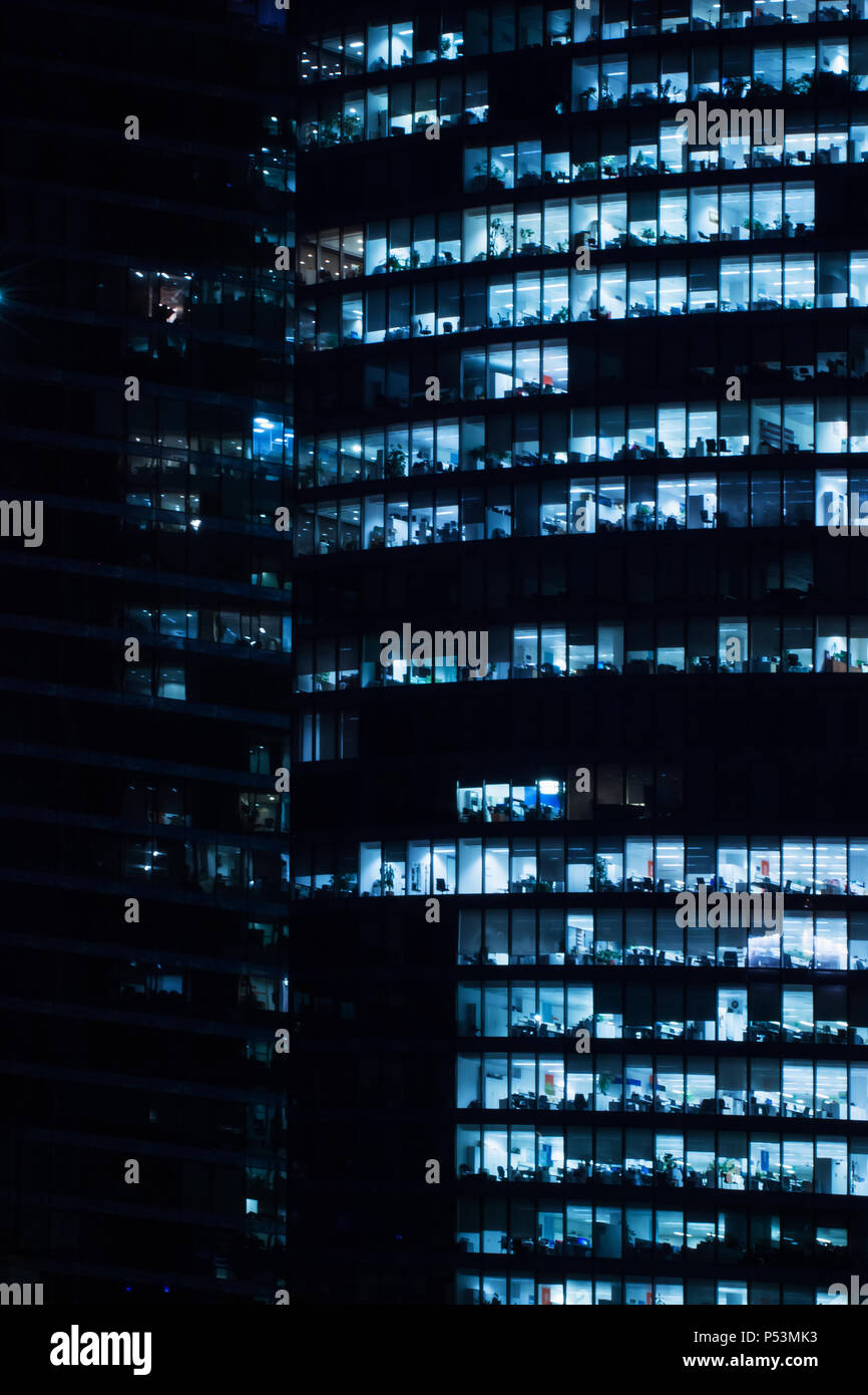 Ventanas de oficina comercial en edificio alto, noche Foto de stock