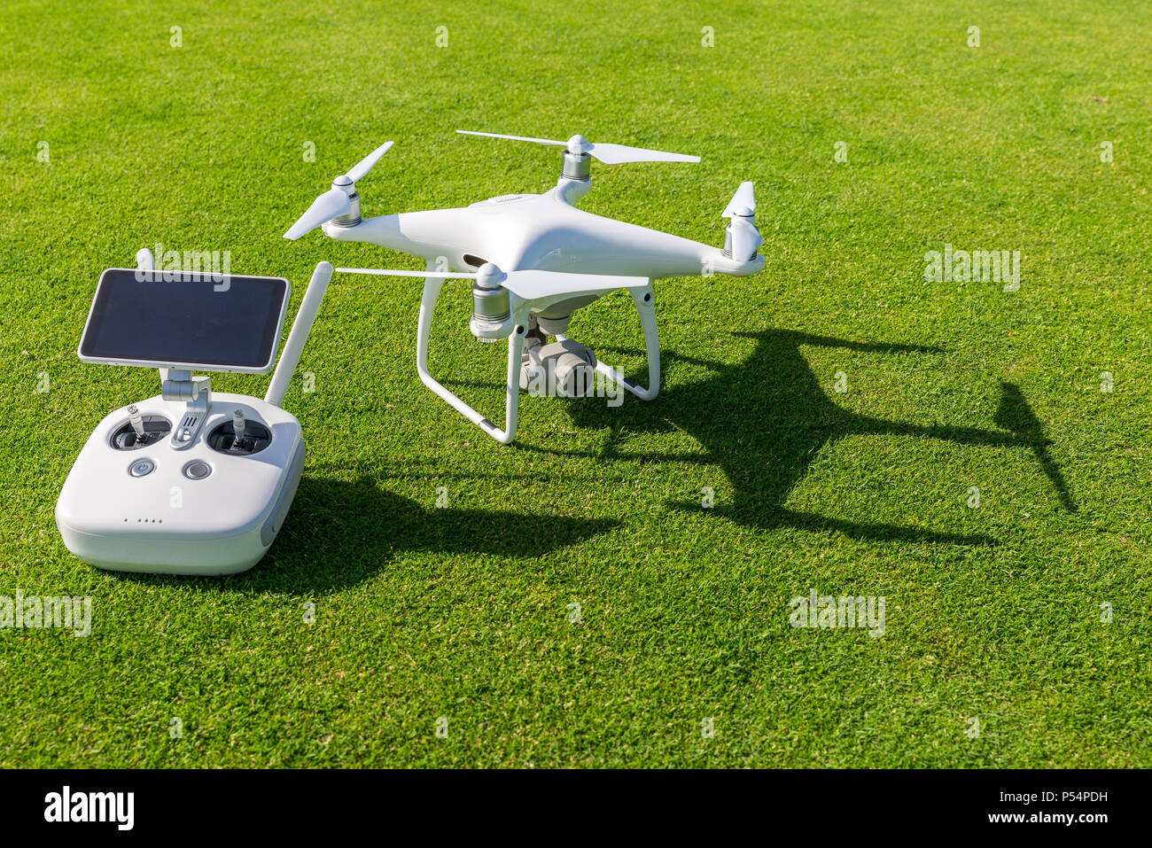 Blanco profesional quadcopter drone cámara con control remoto desde arriba  contra el pasto verde en segundo plano Fotografía de stock - Alamy