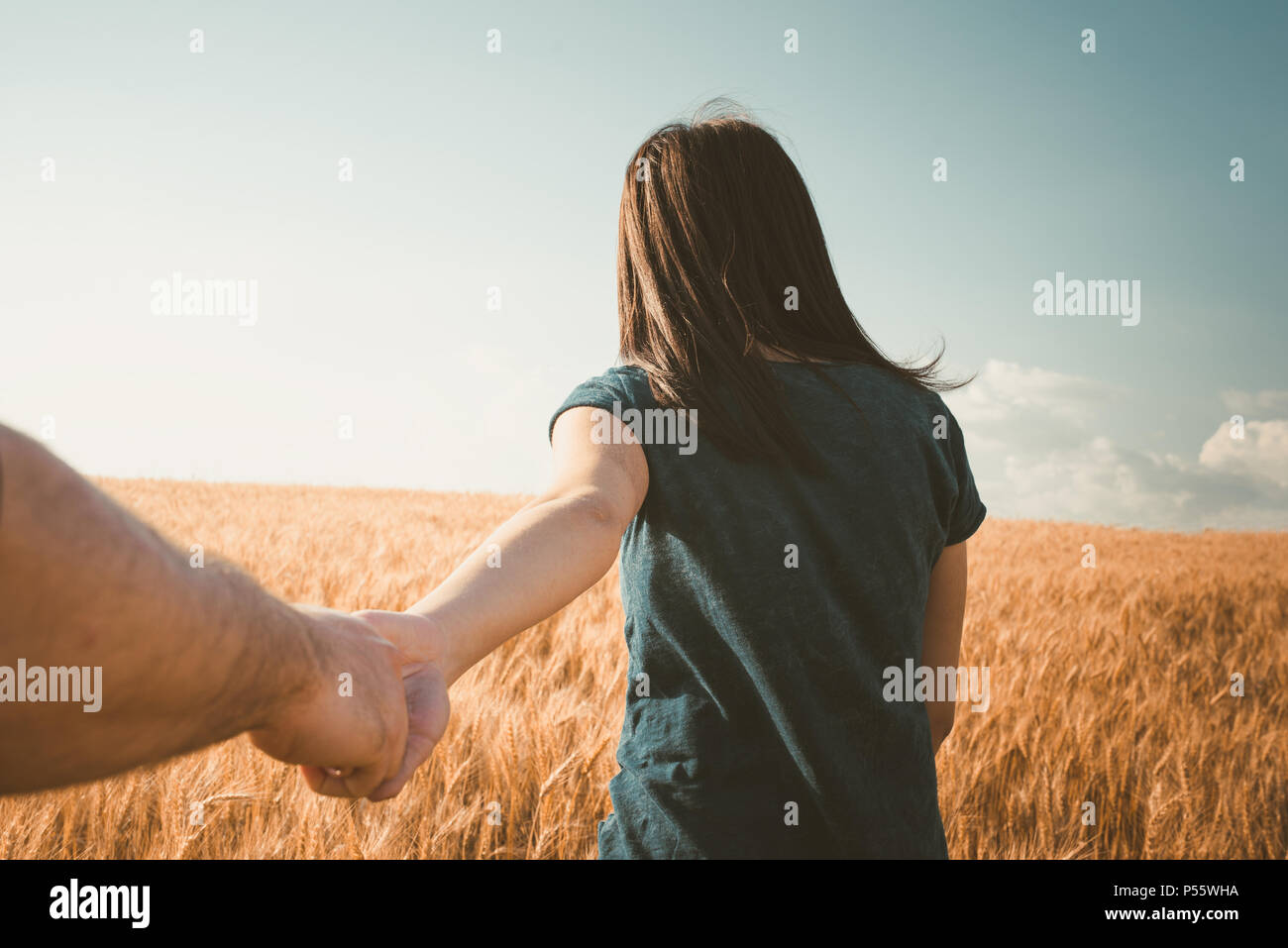 Vista trasera foto de joven mujer caminando con su novio en el campo de hierba. Par disfrutar de un paseo a través de las tierras de pasto Foto de stock