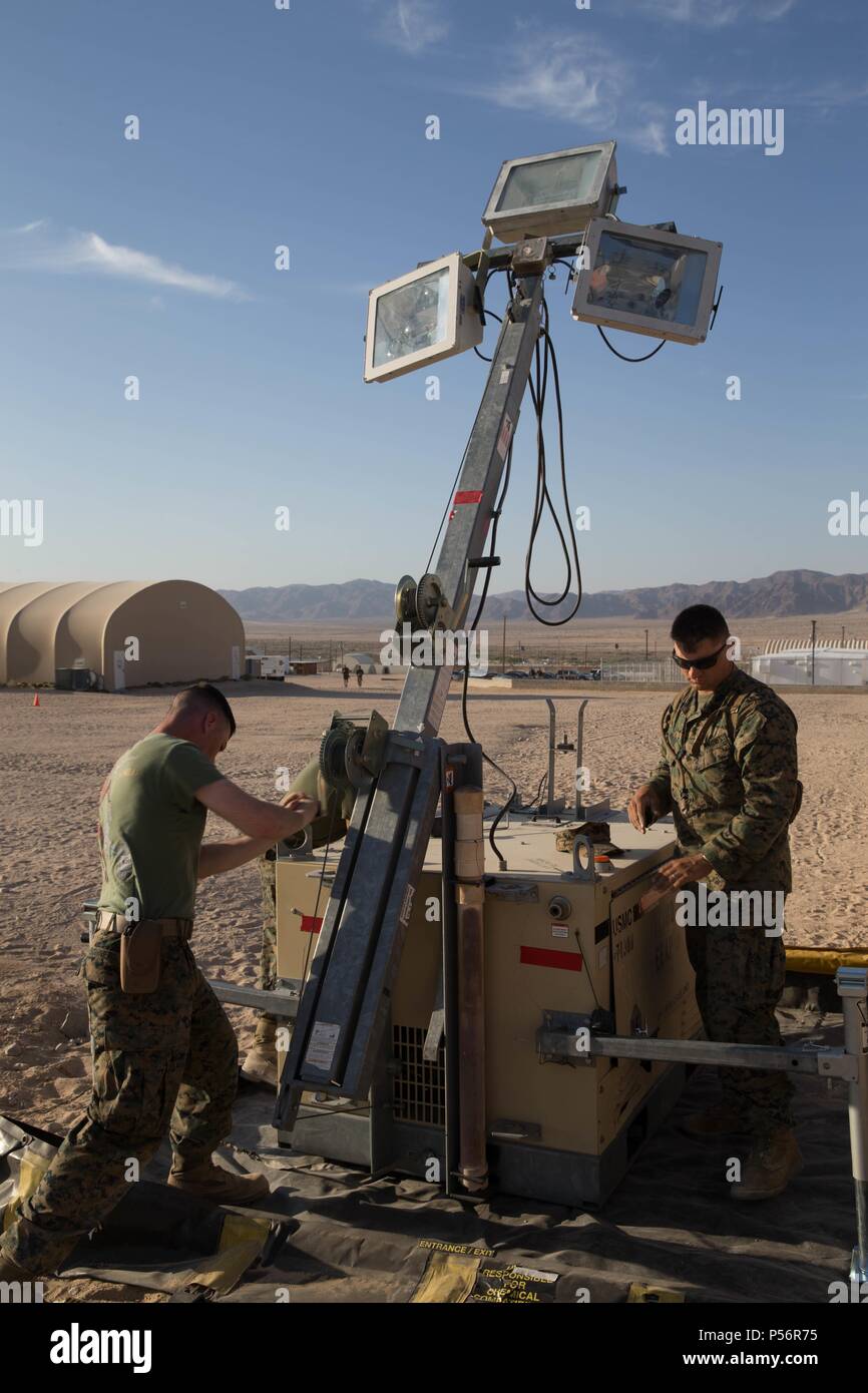 El Sargento. Lucas blanco, un ingeniero técnico de sistemas eléctricos de equipos con la empresa de mantenimiento, luchar contra el batallón de logística 451 del Regimiento de logística de combate, 45, 4º Grupo de Logística Marítima, y Lance Cpl. Eli Sommers, un técnico de refrigeración y aire acondicionado con utilidades, CLR-45, 4º MLG, levantar un foco durante el ejercicio de capacitación integrado 4-18 en la Infantería de Marina Centro de combate aire-tierra Twentynine Palms, California, 12 de junio de 2018, 12 de junio de 2018. Infantes de Marina con el elemento de apoyo de ejercicio de ITX 4-18 proporcionó el servicio de alimentos, procesamiento de llegada y salida, combustible a granel, en el campamento de ingeniería Foto de stock