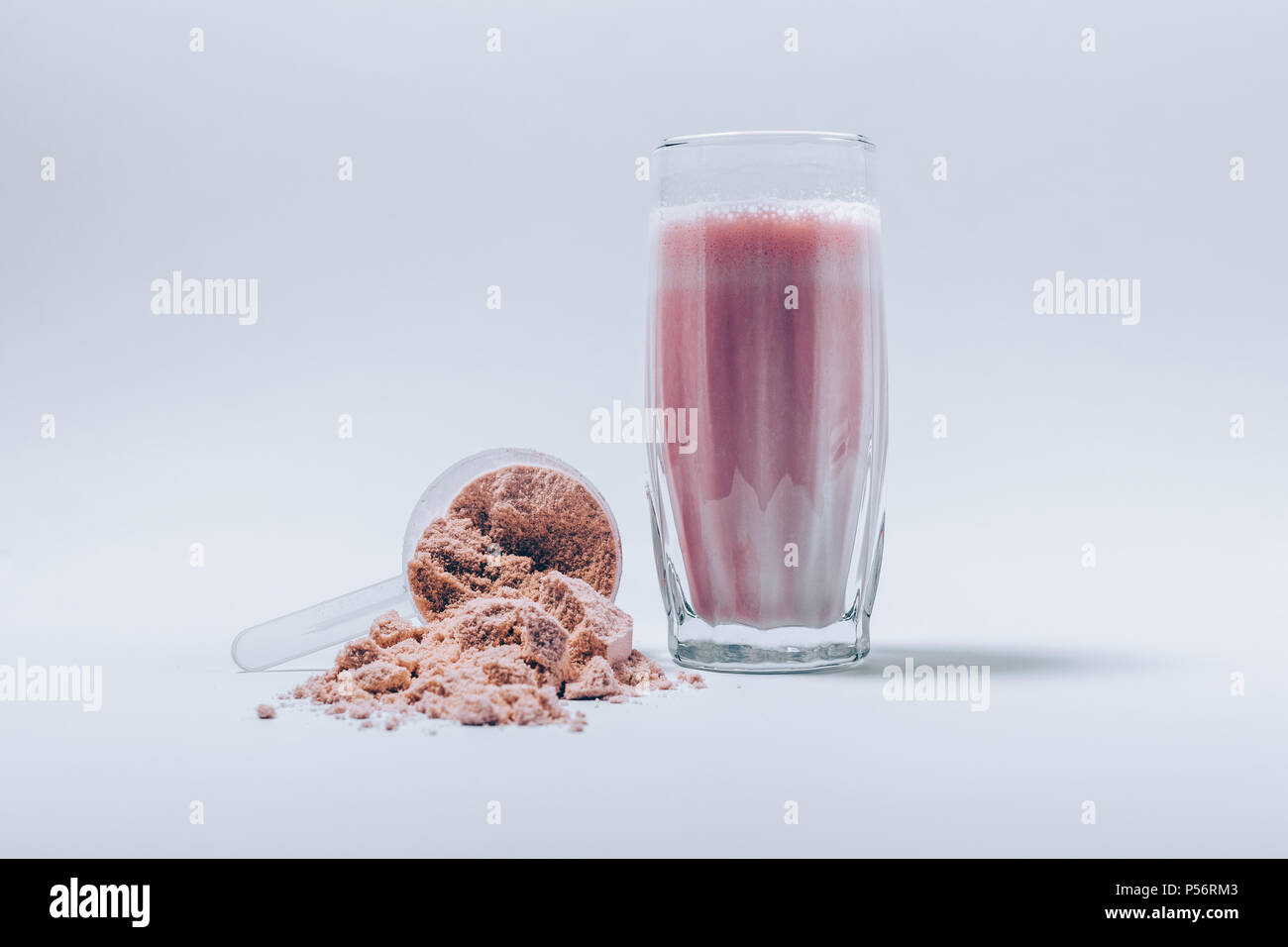 Batido de proteína de suero de leche recién hechas en un vaso y cuchara de  polvo fino en el cuadro blanco. Suplementos deportivos bebida Fotografía de  stock - Alamy