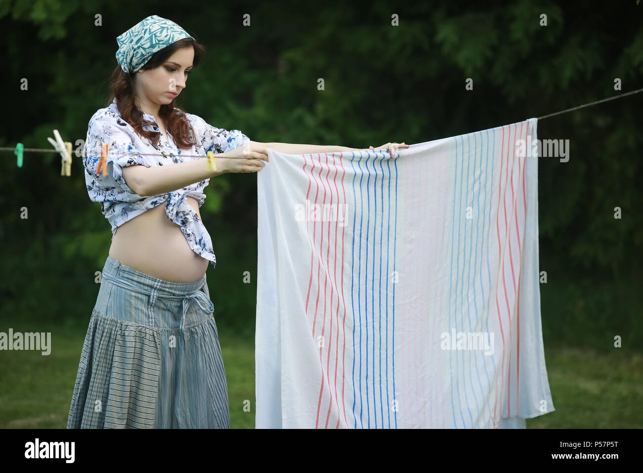 Mujer embarazada colgando a lavar su ropa en la cuerda para secar en la  naturaleza Fotografía de stock - Alamy