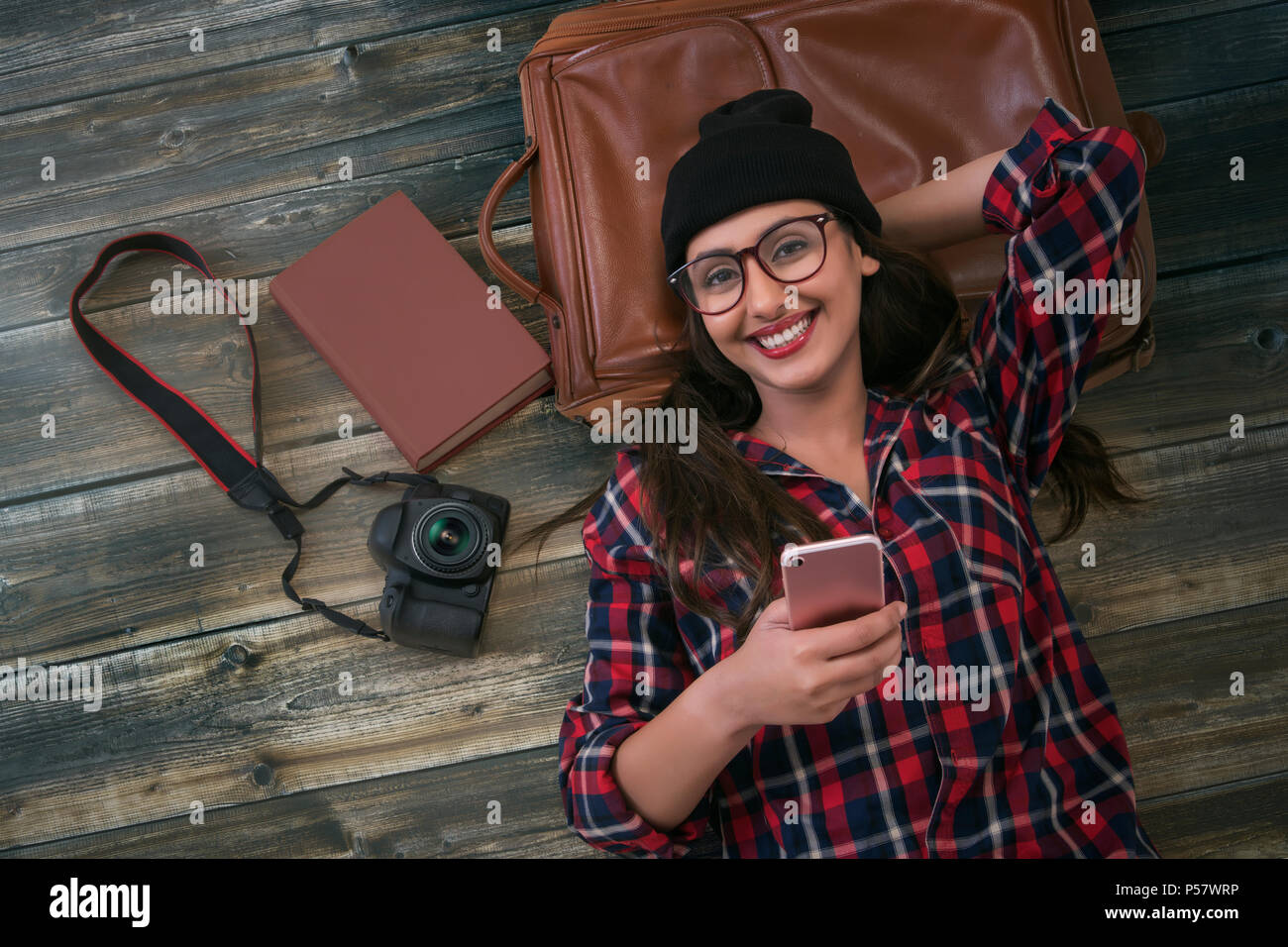 Teléfono holding turístico femenino acostado sobre fondo de madera Foto de stock