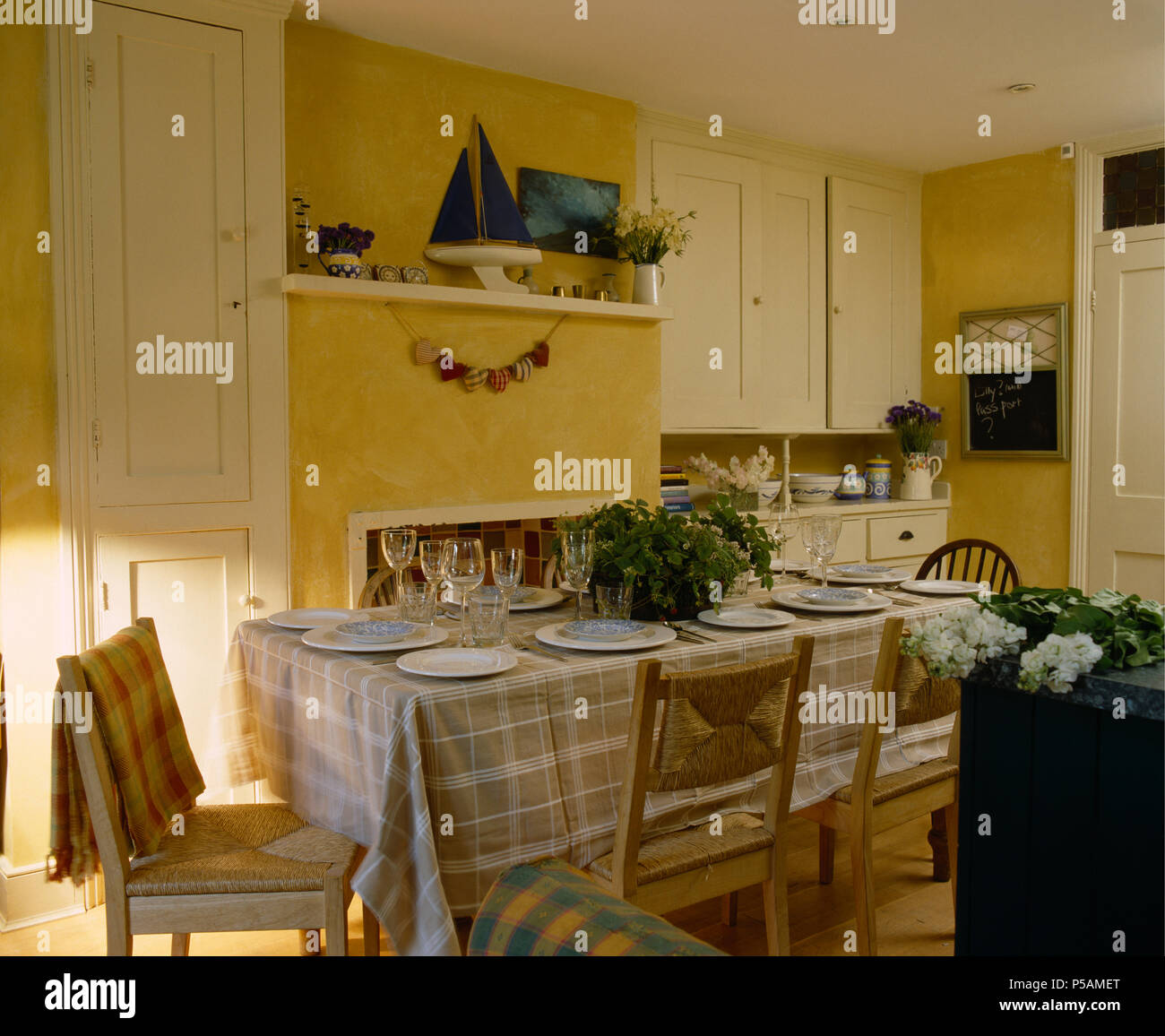 Comprobar Beige paño en mesa para comer en casa cocina comedor con sillas asentada rush. Foto de stock
