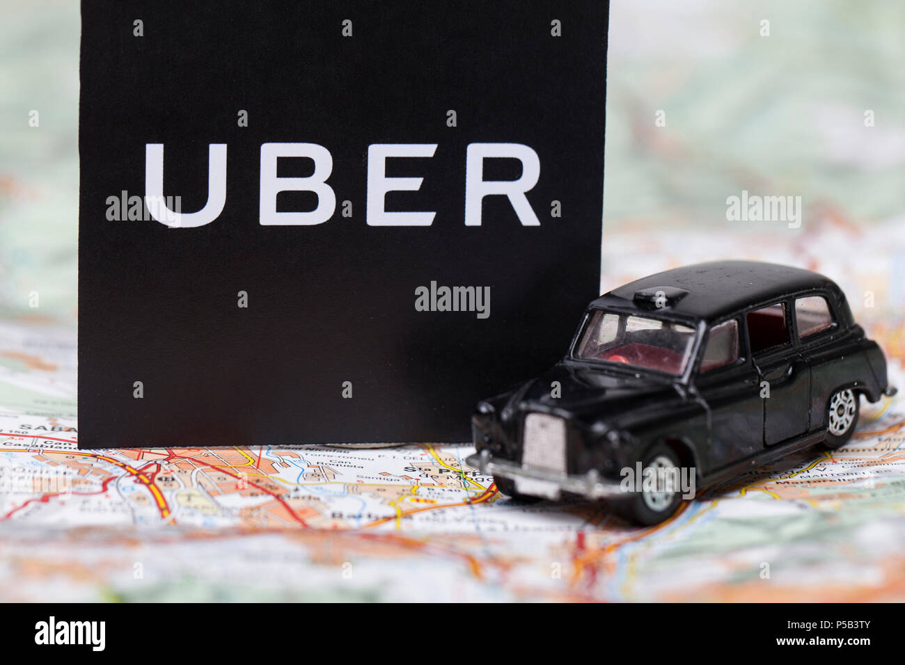 Londres, Reino Unido - 23 de marzo de 2017: Una fotografía de la Uber logotipo con un negro estilo londinense taxi coche de juguete. Uber es un popular servicio de transporte taxi estilo app Foto de stock