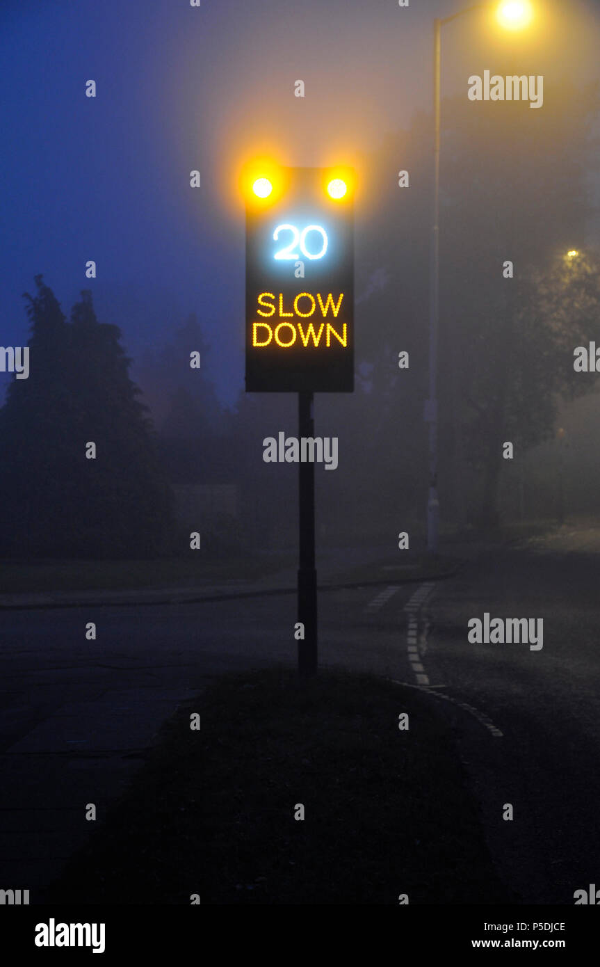 Una señal de tráfico muestra el límite de velocidad en una noche neblinosa. Foto de stock