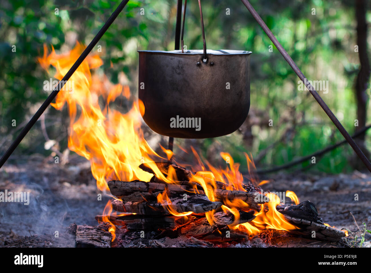 Pot turística colgando sobre el fuego sobre un trípode. Cocinar en la  campaña Fotografía de stock - Alamy