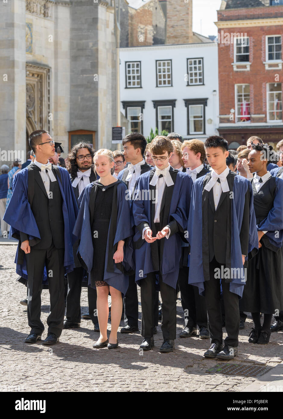 Cambridge, Reino Unido. Miércoles 27 de junio de 2018. Vestida con trajes  académicos oficiales, graduands de Trinity College, Universidad de Cambridge,  Reino Unido, esperando en una cola ordenada para entrar en la