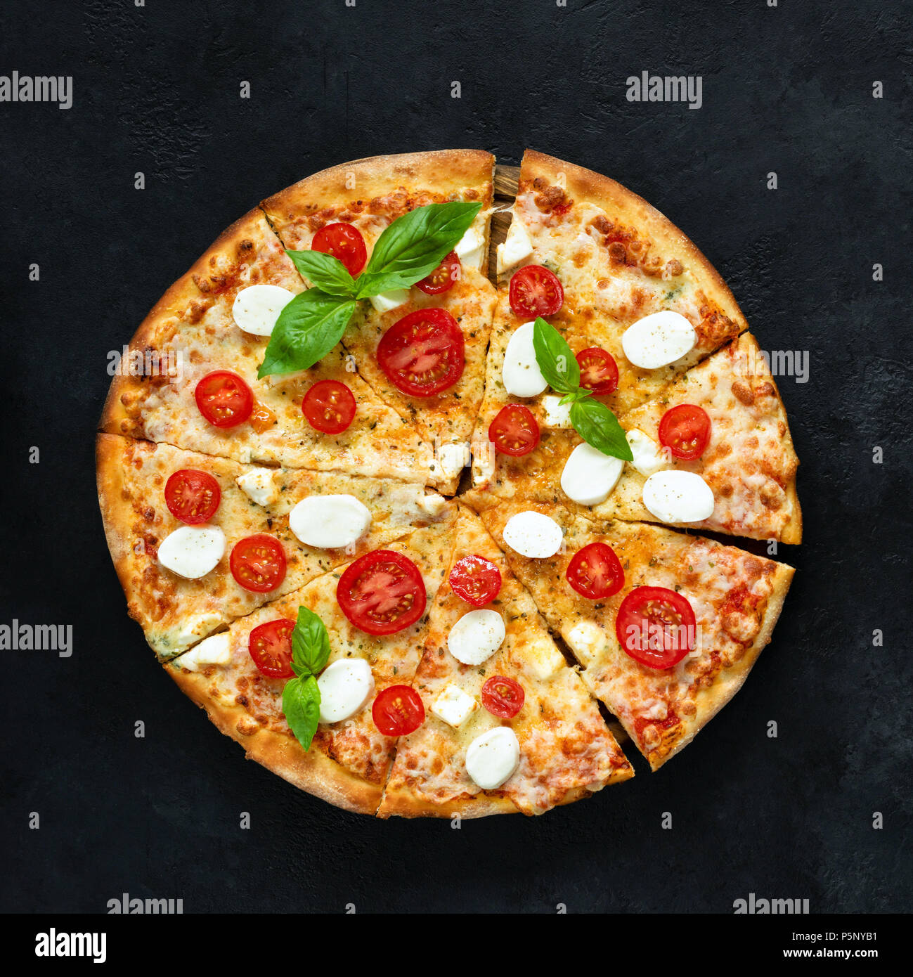 Pizza con queso mozzarella, tomate y albahaca negra sobre fondo de hormigón, vista superior, recortar cuadrados Foto de stock