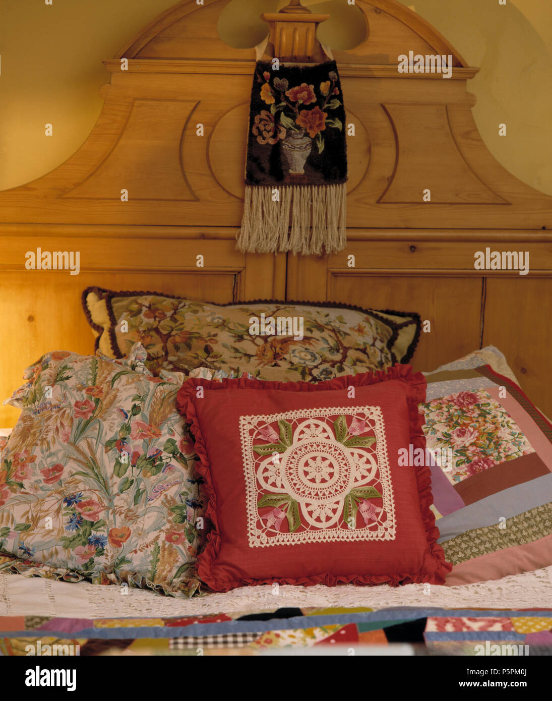 Close-up de flores y cojines de patchwork en cama con cabecero de pino  vintage Fotografía de stock - Alamy