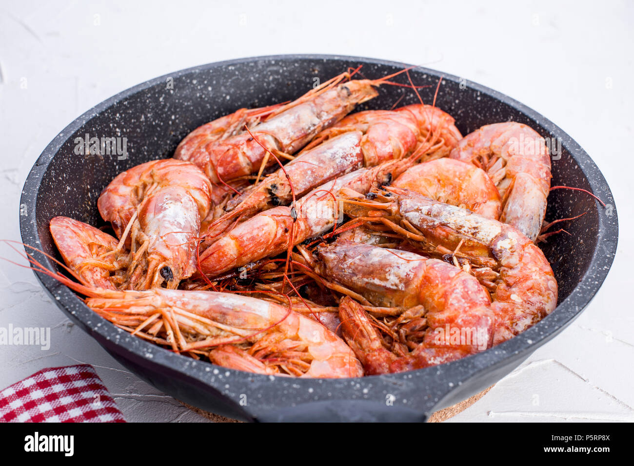 Grandes camarones fritos en una sartén. En una tabla en blanco. Almuerzo de mariscos. Espacio libre para el texto. Espacio de copia Foto de stock