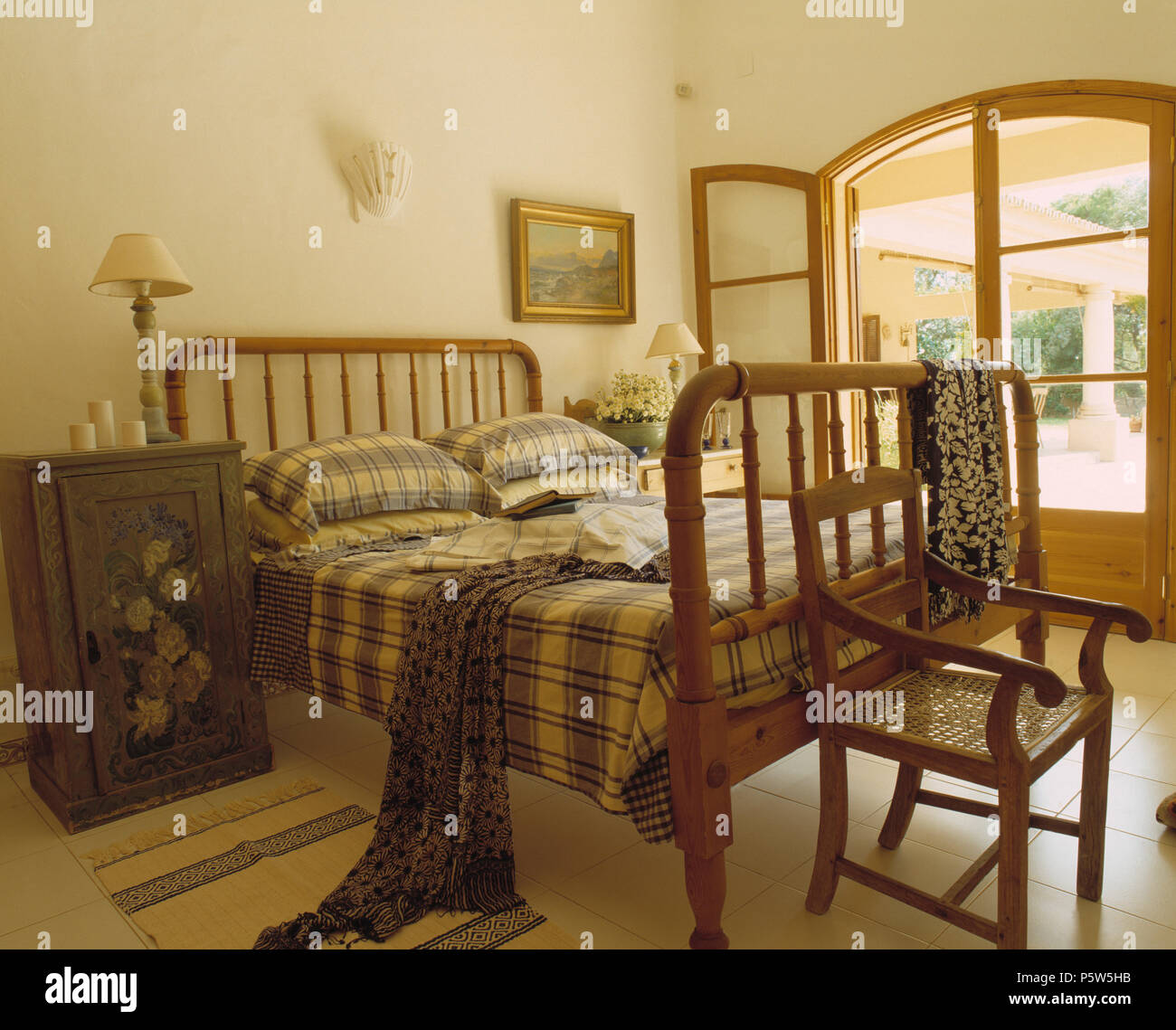 Armario de madera pintada al lado de la cama con marcada enmarcadas en  portugués de la ropa de cama dormitorio con ventanas francesas Fotografía  de stock - Alamy