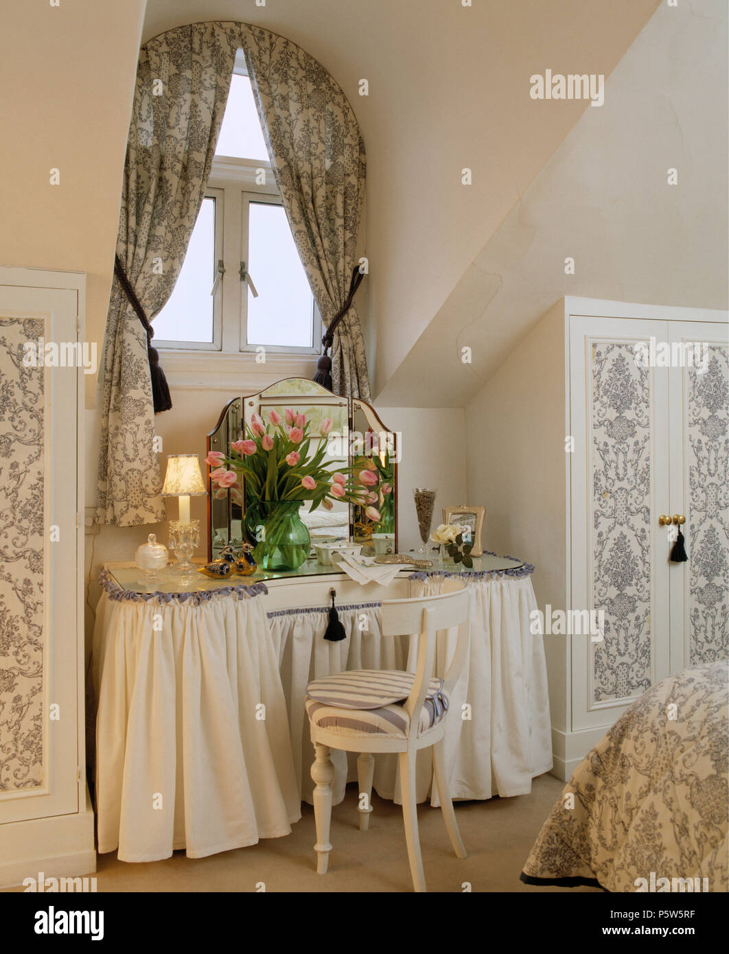 Negro+blanco cortinas florales en ventana encima de tocador con faldón  blanco en buhardilla dormitorio con armarios empotrados Fotografía de stock  - Alamy