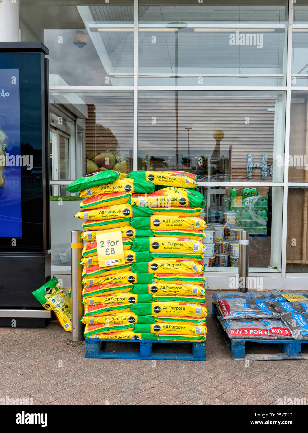 Palet lleno de bolsas con abono fuera de un supermercado Tesco Foto de stock