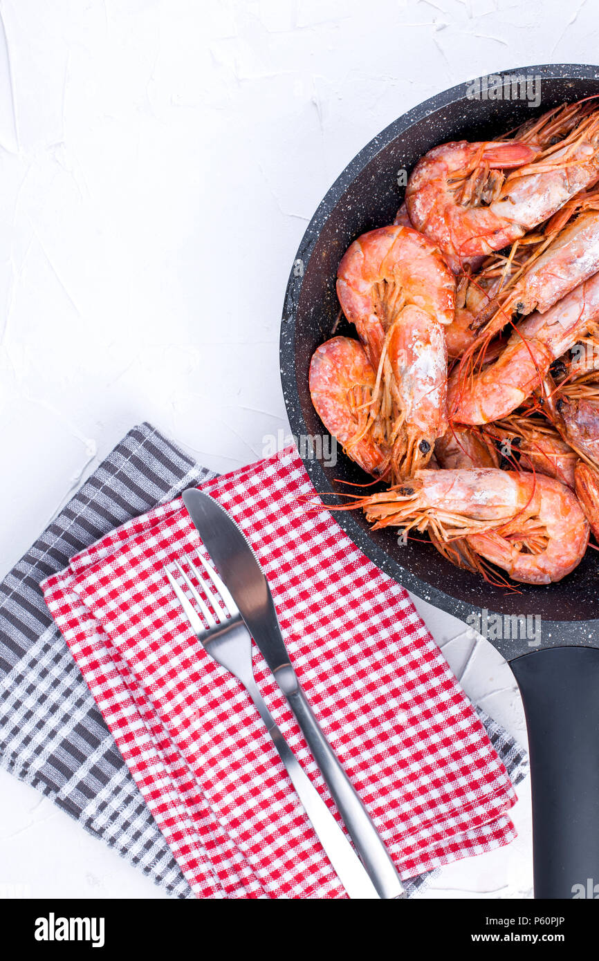 Grandes camarones fritos en una sartén. Sobre un fondo blanco y una tabla tabla toalla. Almuerzo de mariscos. Espacio libre para el texto. Espacio de copia Foto de stock