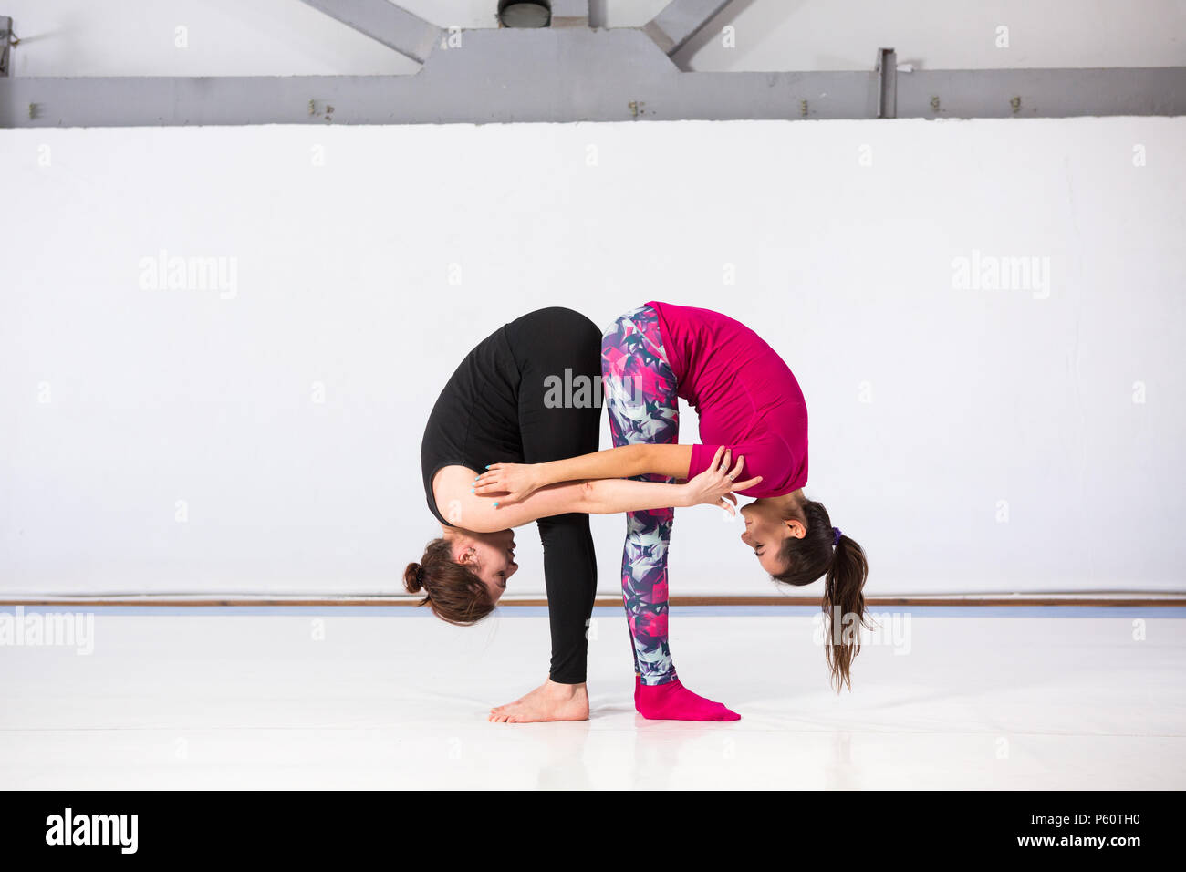 El tema es el deporte y un estilo de vida saludable. La acrobacia y la superficie. Dos personas de mujeres jóvenes con una buena figura haciendo ejercicios en un par, el trabajo El tema es el deporte y un estilo de vida saludable. La acrobacia y la superficie. Dos personas de mujeres jóvenes con una buena figura haciendo ejercicios en un par, el trabajo